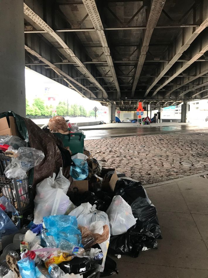 Residents make their best attempt to collect trash in the I-44 encampment, for which the city has refused to provide a dumpster.