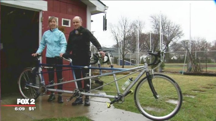 Image description: Nino and Marie Pacini pose beside a triple tandem bicycle that they ride with the help of a sighted friend. Source: Fox 2 Detroit.