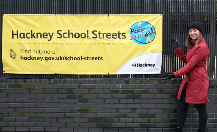 The author in front of a community outreach sign at a Hackney school. Photo: Gary Manhine