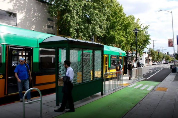 A protected bike lane on Roosevelt Way wraps behind the bus shelter, improving operations for both modes. Photo: Doug Trumm