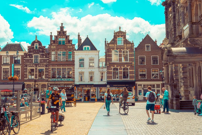 A pedestrian plaza in Delft, the Netherlands, full of people walking and biking.