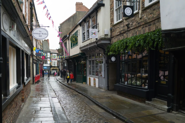 A pedestrian-friendly street in Scotland, lined with shops and people walking on the sidewalks. 